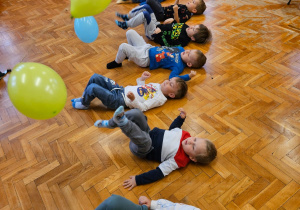 zabawa ruchowa - chłopcy leżą na plecach i starają się kopnąć balony zawieszone nad nimi na linien