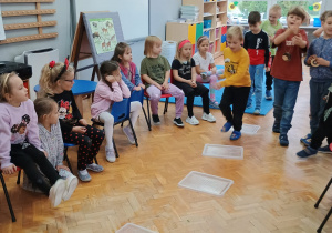 zabawa skoczna - chłopcy przeskakują rozłożone pokrywki od pojemników