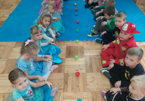 dzieci bawią się piłeczkami siedzą w dwóch rzędach