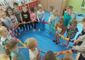 przedszkolaki w sali w czasie zabaw z kolorową liną krążą w kole