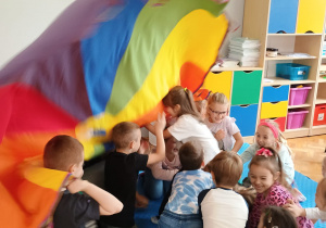 przedszkolaki w sali w czasie zabaw z chustą animacyjną wbiegają pod nią