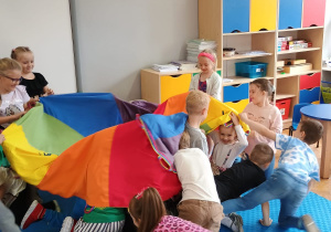 przedszkolaki w sali w czasie zabaw z chustą animacyjną chowają się pod nią