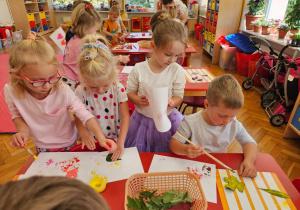 przedszkolaki podczas malowania liści farbą i odciskania ich na kartce