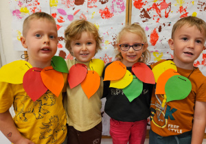 prace plastyczne - dzieci prezentują korale z liści wyciętych z kolorowego papieru i nałożonych na sznurek