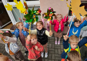 dzieci na tarasie pokazują swoje wiatraczki i liście