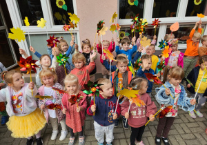 dzieci na tarasie pokazują swoje wiatraczki i liście