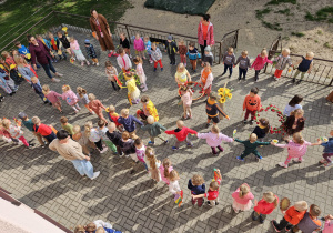 przedszkolaki na tarasie ustawiają się do korowodu z jesiennymi akcesoriami