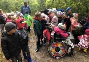 dzieci w lesie a pośród nich dziewczynka na wózku