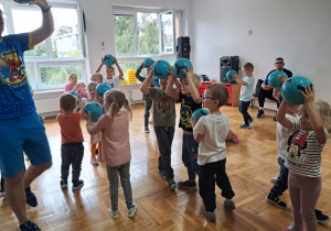 dzieci trzymają piłki nad głowami