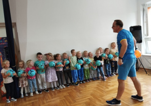 przedszkolaki stoją przed trenerem z piłkami