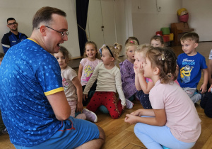 dzieci siedzą na piłkach i rozmawiają z trenerem