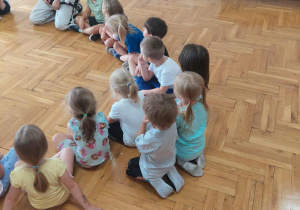 dzieci siedzą w kole z trenerem