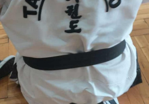 trener w kimonie z napisem taekwon-do siedzi tyłem