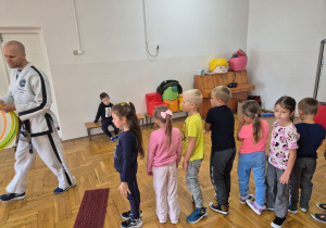 trener objaśnia zabawę stojącym w rzędzie dzieciom
