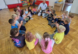 dzieci siedzą w kole z trenerem