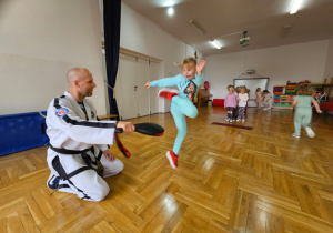 dzieci ćwiczą wyskoki celując nogą w łapkę trzymaną przez trenera