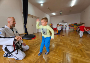 przedszkolaki ćwiczą trafienia uderzając ręką w łapkę trzymaną przez trenera