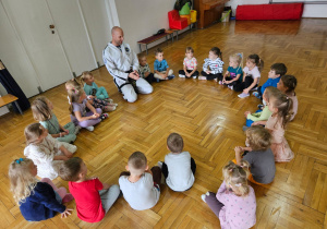 dzieci siedzą w kole z trenerem