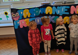 dziewczynka jest pasowana na przedszkolaka, zostaje dotknięta wielką kredką w ramię