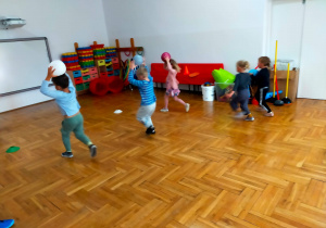 przedszkolaki biegną z piłkami uniesionymi nad głową