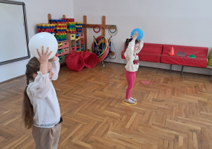 dziewczynki stoją w kókach i trzymają piłkę na głowie