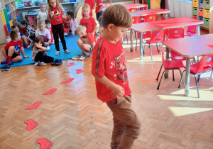 dzieci poruszają się boso po czerwonych stopach naklejonych na podłodze
