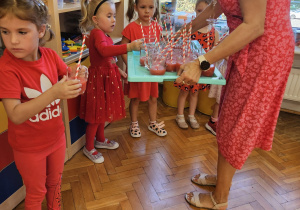 nauczycielka częstuje dzieci sokiem arbuzowym