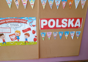 tablica z symbolami narodowymi, napisem Polska o raz wykonanymi przez dzieci proporczykami z napisem 11 listopada
