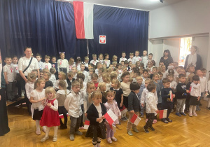 zdjęcie zbiorowe dzieci z nauczycielkami na tle flagi Polski