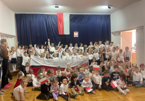zdjęcie zbiorowe dzieci z nauczycielkami na tle flagi Polski