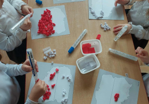 dzieci wykonują pracę plastyczną w kolarach biało czerwonych