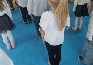 dzieci stoją w postawie zasadniczej podczas śpiewania hymnu