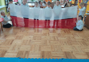 chłopcy trzymają długą flagę polską