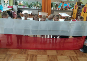 dziewczynki trzymają długą flagę polską