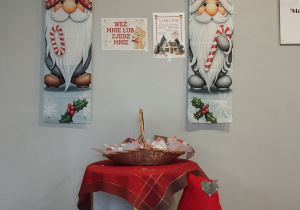 Mikołaje obok stoliczka z poczęstunkiem - pierniczkami dla wchodzących do przedszkola