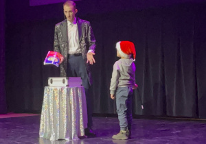 na scenie stoi chłopiec obok Czarodzieja