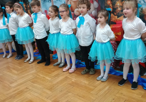 przedszkolaki stoją i śpiewają stojąc w półkolu