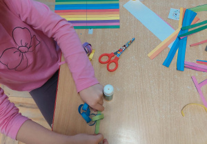 dziewczynka wkłada pasek w kółko tworząc nowe oczko łańcucha