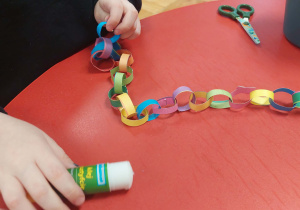 dziecko robi lańcuch z kolorowych pasków