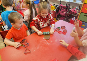 dziewczynka rozwałkowuje resztki ciasta na stoliku