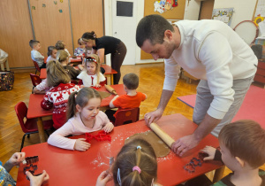 rodzice wałkują ciasto na pierniczki na stolikch, przy których siedzą dzieci