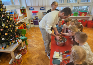 dzieci sprawdzają zarobione ciasto na pierniki, dotykają i wąchają