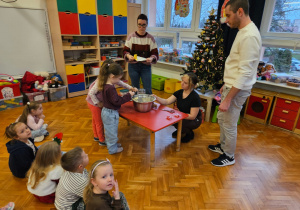 dziewczynki wrzucają kawałki masła do miski pod okiem rodziców