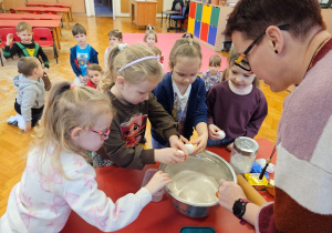 dziewczynki wbijają jajka do miski pod okiem mamy