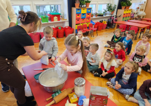 dzieci wspują do miski gotową msę piernikową pod okiem mamy