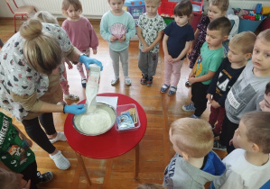 dzieci patrzą jak pani wsypuje mąkę do miski