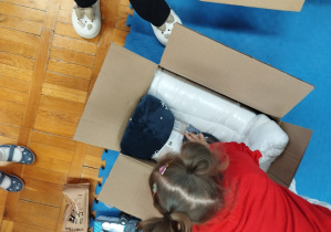 dziecko wkłada upominki do tekturowego pudełka