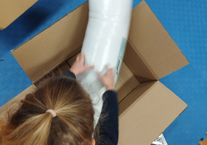 dziecko wkłada upominki do tekturowego pudełka