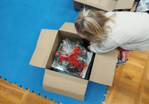 dzieczynka wkłada upominki do tekturowego pudełka