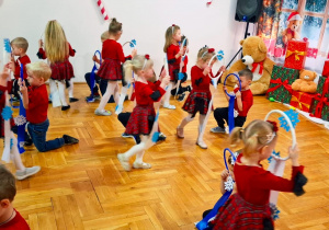 przedszkolaki w czerwonych strojach podczas występu tańczą z obręczami